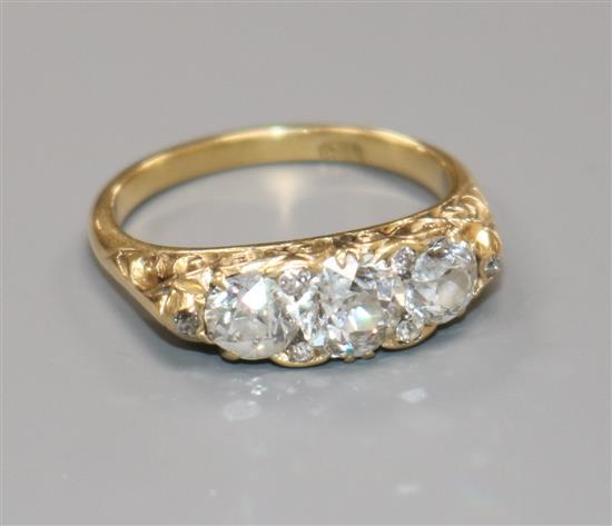An 18ct gold and three stone diamond ring, with diamond set spacers, size N.